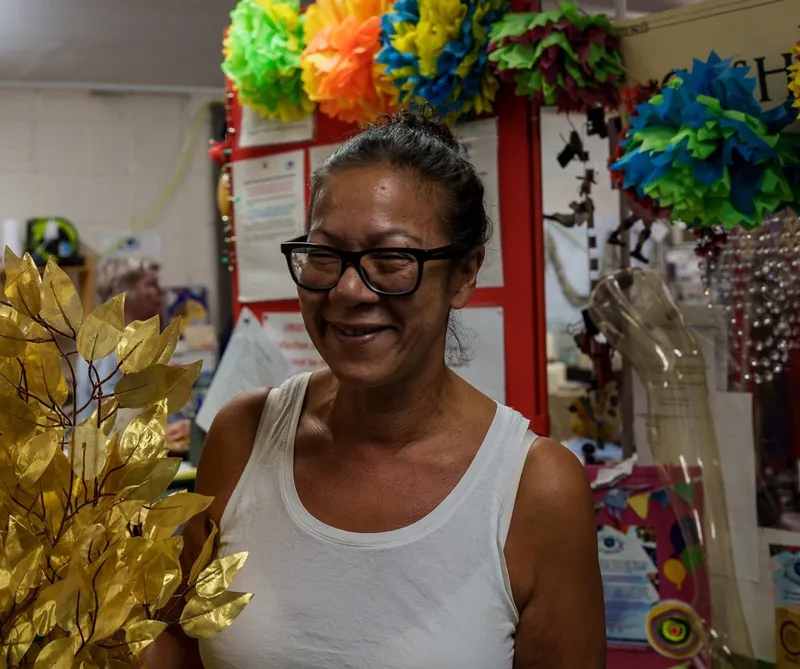 A member smiling beside an armful of gold-leaf branches in the store