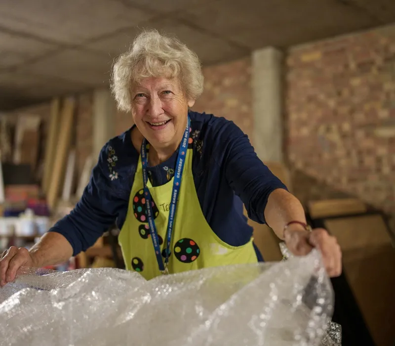 A smiling volunteer unpacking a delivery of donated materials