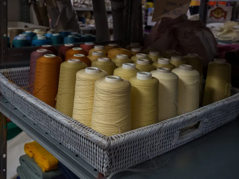 A basket of donated thread cones in shades of cream and gold