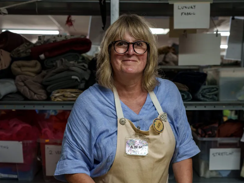 A volunteer in an apron at the fabric shelves