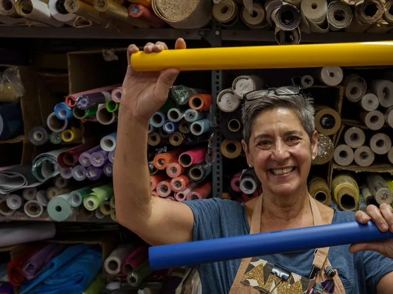 A smiling volunteer holding up a roll of coloured paper in front of the paper store