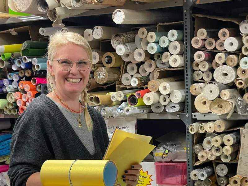 A volunteer sorting rolls of card and paper onto labelled storage shelves