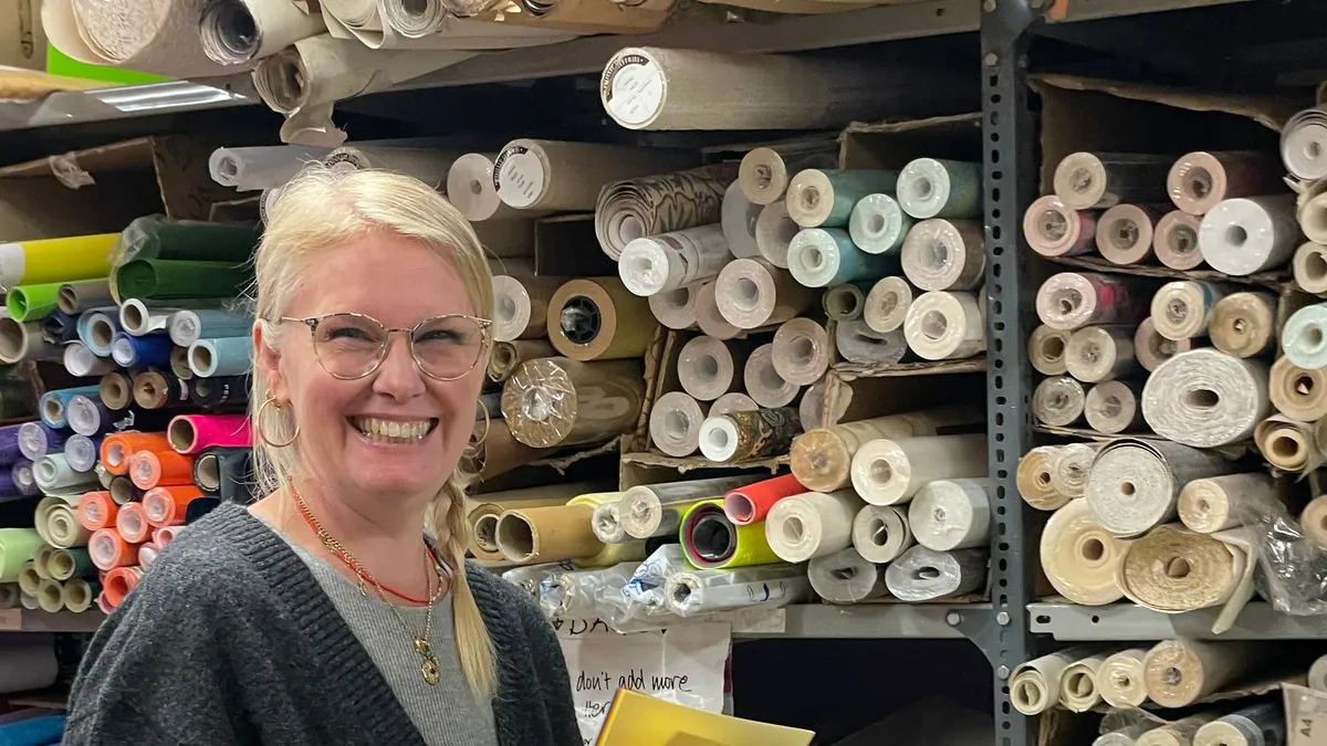A volunteer sorting rolls of card and paper onto labelled storage shelves